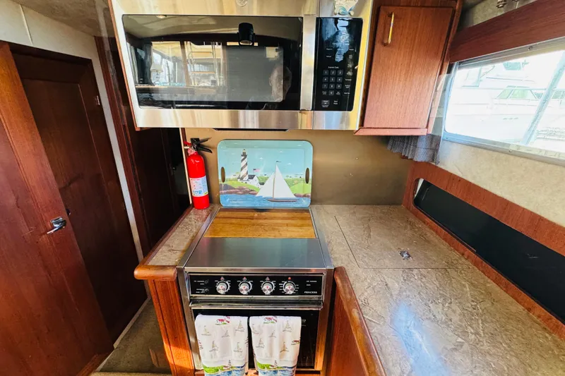 Slide: The Image of 1990 Bayliner 3888 Motoryacht kitchen with microwave, stove, and nautical decor. - 30