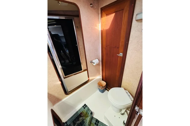 Slide: The Image of Bathroom interior of 1990 Bayliner 3888 Motoryacht with toilet, mirror, and wooden door. - 34