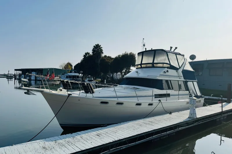 Slide: The Image of 1990 Bayliner 3888 Motoryacht docked at a marina under clear skies. - 5