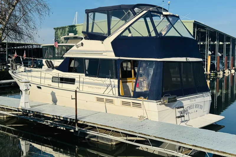 Slide: The Image of 1990 Bayliner 3888 Motoryacht docked at marina, featuring blue canopy and white hull. - 6
