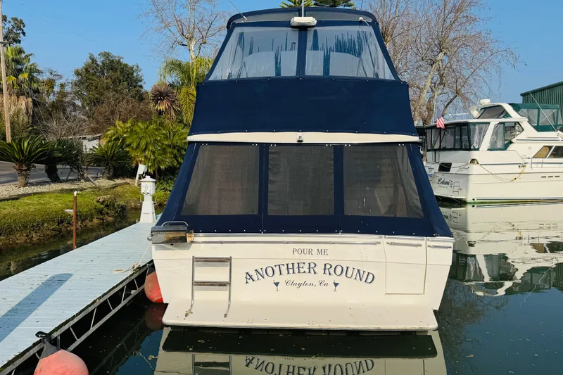 Slide: The Image of 1990 Bayliner 3888 Motoryacht docked, named "Another Round," with blue canopy. - 8