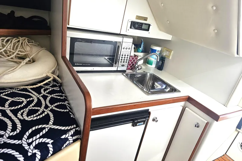 Slide: The Image of 2003 Tiara Yachts 2900 Coronet interior with kitchenette, microwave, sink, and nautical-themed decor. - 32