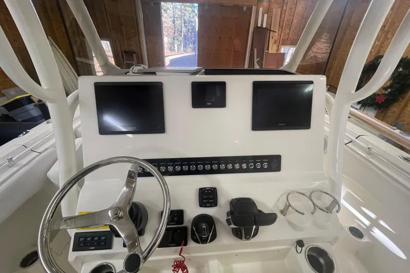 Slide: The Image of 2023 Key West 263 FS boat dashboard with dual screens and steering wheel in a garage setting. - 24