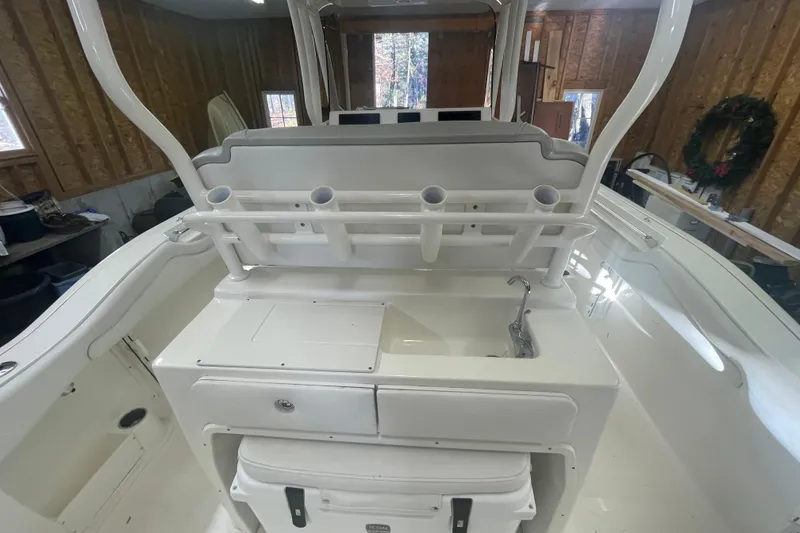 Slide: The Image of 2023 Key West 263 FS boat interior with rod holders and sink in a wooden garage. - 26