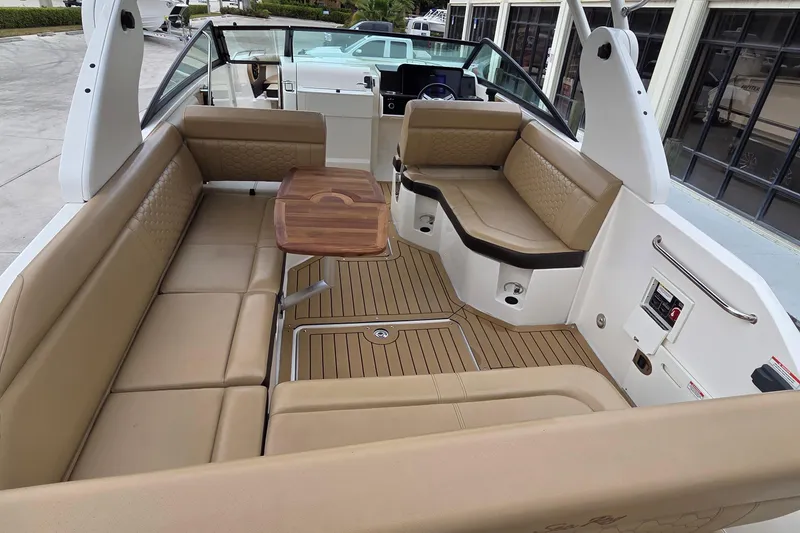 Slide: The Image of 2020 Sea Ray SDX 250 Outboard boat interior with tan seating and wooden table. - 10