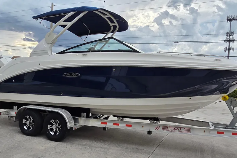 Slide: The Image of 2020 Sea Ray SDX 250 Outboard boat on trailer, blue and white design, parked outdoors. - 4