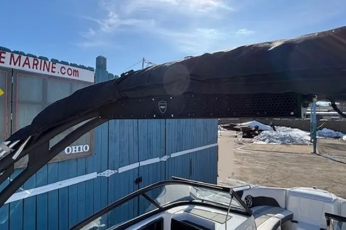 Slide: The Image of 2021 Yamaha Boats 212XD with covered tower, parked near a blue building in Ohio. - 36