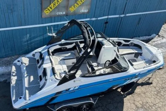 Slide: The Image of 2021 Yamaha Boats 212XD, blue and white, parked on a trailer outside a blue building. - 6