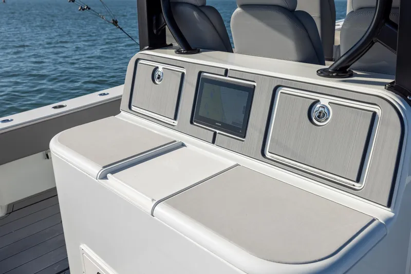 Slide: The Image of 2024 Freeman 47 boat console with navigation screen and storage compartments on open water. - 19