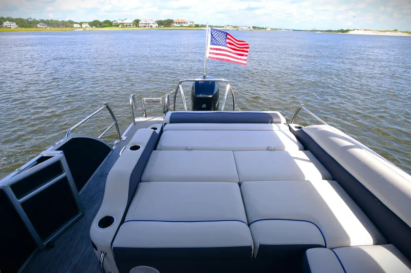 Slide: The Image of 2022 Barletta Corsa 25U pontoon boat with American flag on a scenic lake. - 12