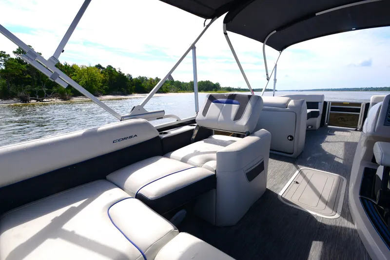 Slide: The Image of 2022 Barletta Corsa 25U pontoon boat interior with plush seating on a scenic lake. - 14