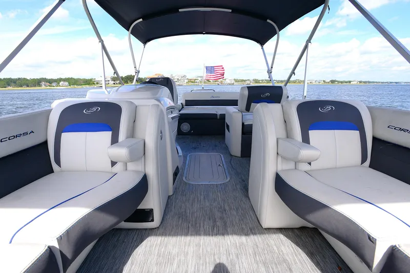 Slide: The Image of 2022 Barletta Corsa 25U pontoon boat interior with plush seating and canopy on a sunny day. - 23
