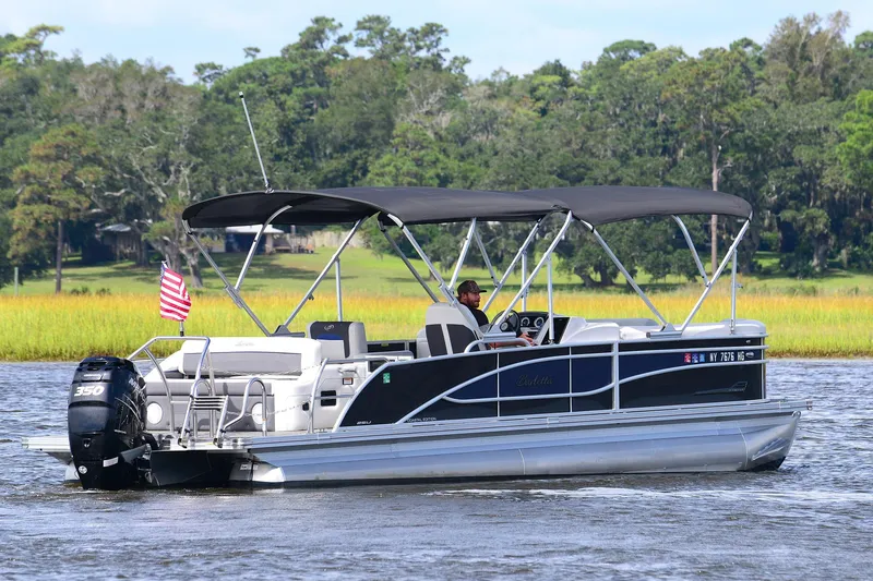 Slide: The Image of 2022 Barletta Corsa 25U pontoon boat cruising on a scenic lake. - 4