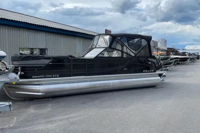 The Image of 2021 Crest Continental 250 SLS pontoon boat parked outdoors under cloudy sky. - 1