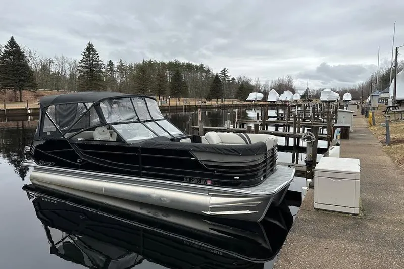 Slide: The Image of 2021 Crest Continental 250 SLS pontoon boat docked at a marina on a cloudy day. - 17