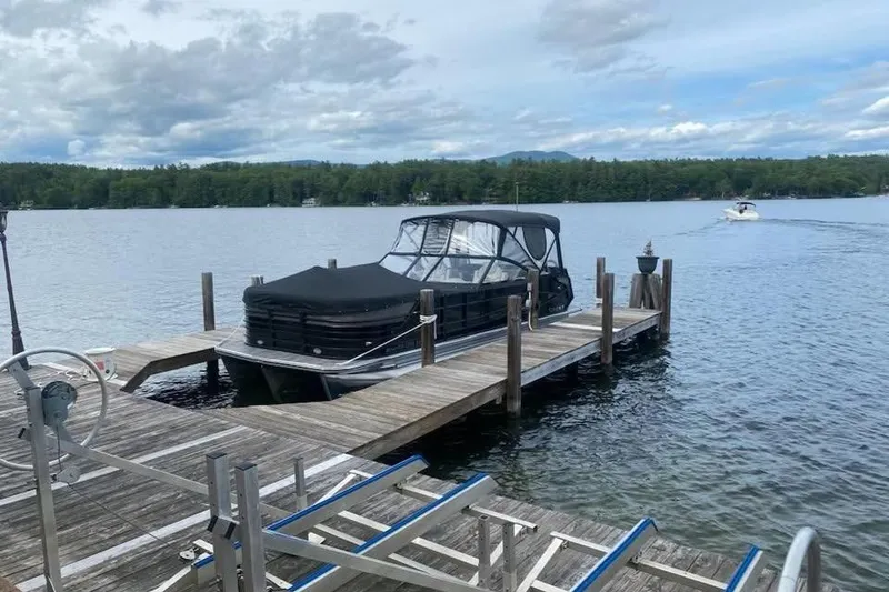 Slide: The Image of 2021 Crest Continental 250 SLS pontoon boat docked on a serene lake. - 3
