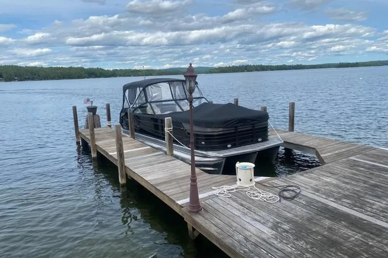 Slide: The Image of 2021 Crest Continental 250 SLS pontoon boat docked on a serene lake. - 4