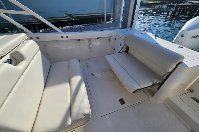 Slide: The Image of 2012 Pursuit C 310 Center Console boat interior with cushioned seating and water view. - 19