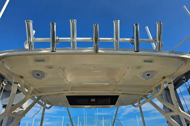 Slide: The Image of 2012 Pursuit C 310 Center Console boat with rod holders and speakers under clear blue sky. - 21