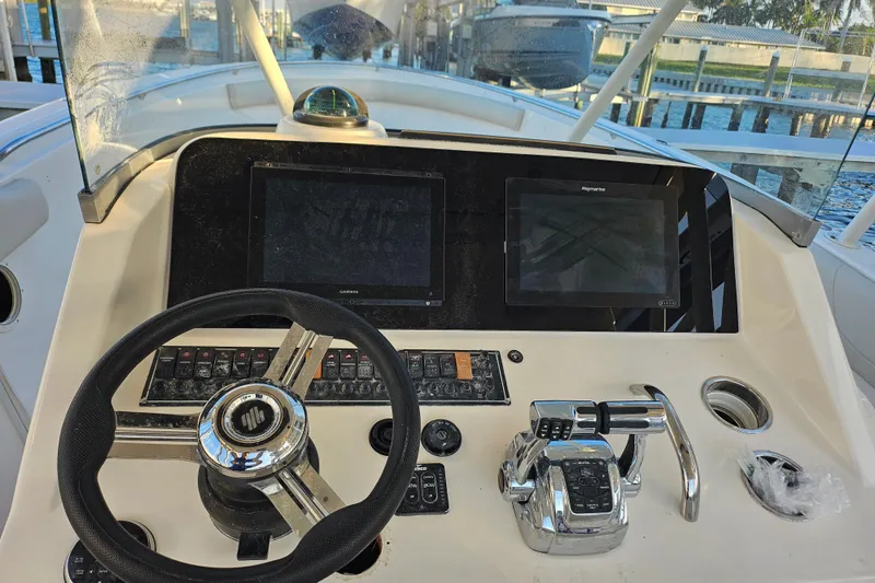 Slide: The Image of 2012 Pursuit C 310 Center Console boat dashboard with steering wheel and navigation screens. - 22