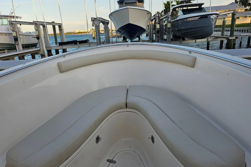 Slide: The Image of 2012 Pursuit C 310 Center Console boat interior with cushioned seating at dock. - 27