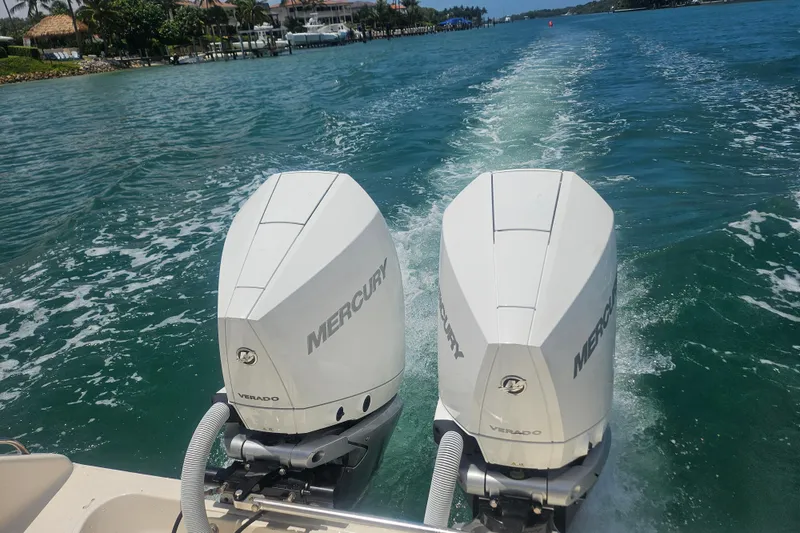 Slide: The Image of Twin Mercury Verado engines on a 2012 Pursuit C 310 Center Console boat in clear waters. - 5