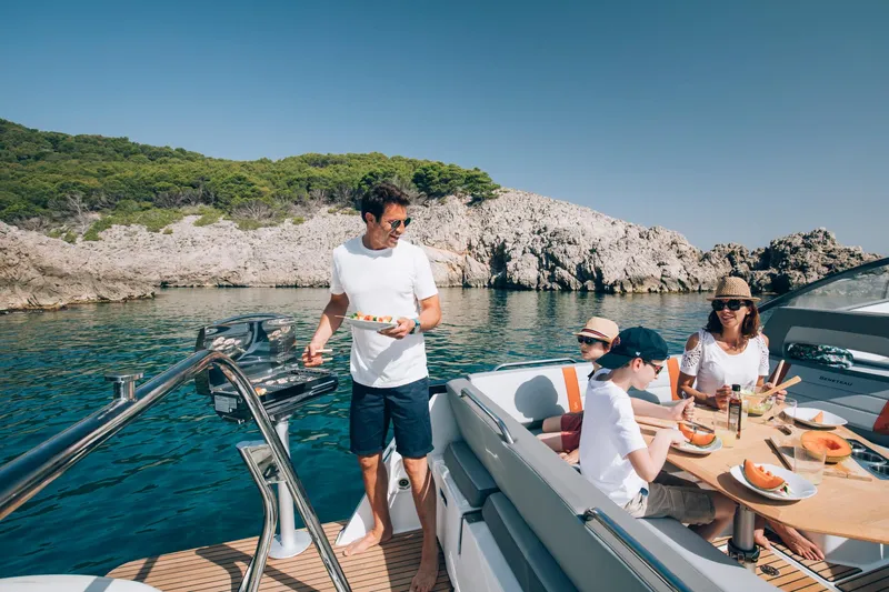 Slide: The Image of Family enjoying a meal on a 2024 Beneteau Flyer 10 boat by the sea. - 19