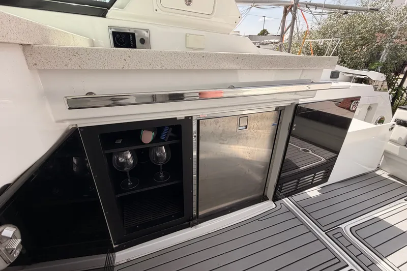 Slide: The Image of 2018 Monterey 360 Sport Coupe yacht kitchenette with countertop, wine glasses, and stainless steel fridge. - 18