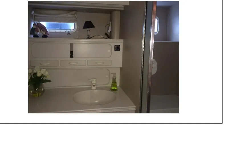 Slide: The Image of 1977 Hatteras 58 Yacht Fisherman interior bathroom with white cabinets and decor. - 13