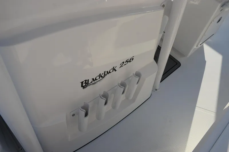 Slide: The Image of 2026 BlackJack 256 Coastal boat interior with rod holders and branding. - 15