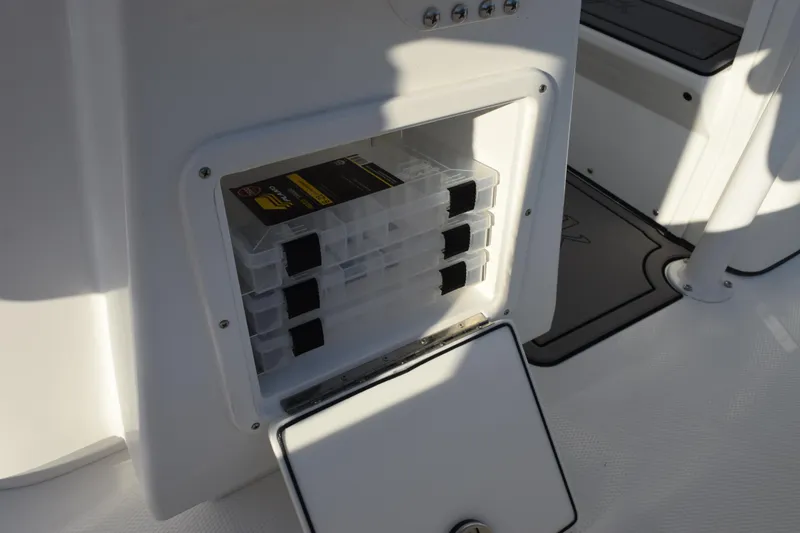 Slide: The Image of Storage compartment on 2026 BlackJack 256 Coastal boat with organized tackle boxes. - 18