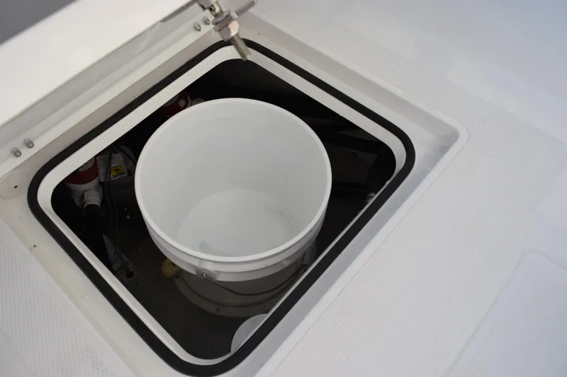 Slide: The Image of Storage compartment with white bucket on 2026 BlackJack 256 Coastal boat. - 20