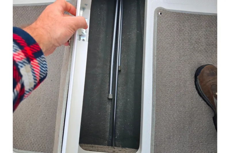 Slide: The Image of Hand opening storage compartment on 2011 Larson LX 850 boat, revealing interior space. - 12