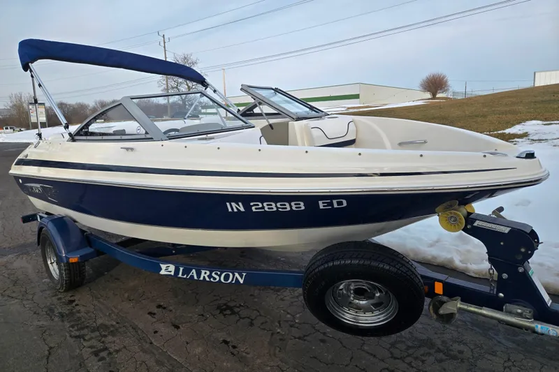 Slide: The Image of 2011 Larson LX 850 boat on trailer, blue and white, parked on snowy pavement. - 5