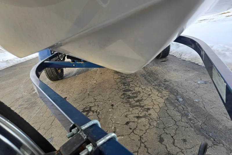 Slide: The Image of Trailer holding a 2011 Larson LX 850 boat on cracked pavement with snow nearby. - 7