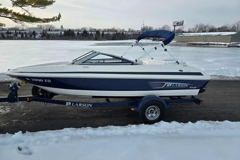 Slide: The Image of 2011 Larson LX 850 boat on trailer, parked by snowy lakeside. - 9