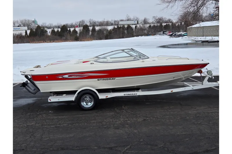 The Image of 2008 Stingray 195 LS/LX/LR boat on trailer, red and white design, parked near snowy lake. - 0