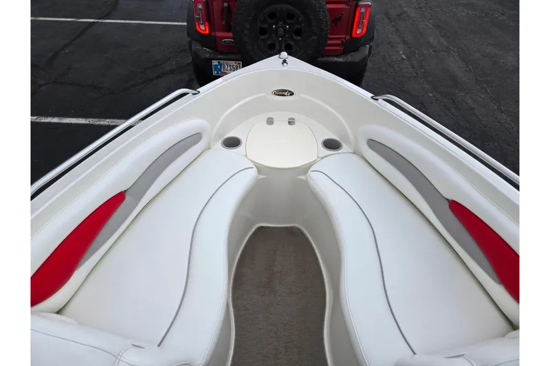 Slide: The Image of 2008 Stingray 195 LS/LX/LR boat interior with white and red seating, parked near a vehicle. - 16