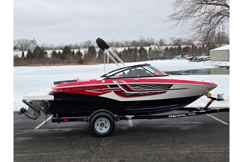 The Image of 2017 Regal 1900 ESX Bowrider on trailer, red and white design, parked near snowy lake. - 0