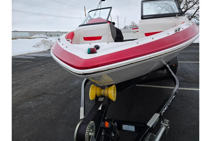 Slide: The Image of 2017 Regal 1900 ESX Bowrider on trailer, red and white design, parked on snowy pavement. - 6