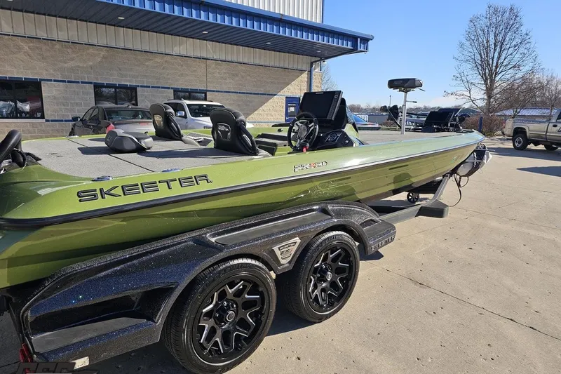 Slide: The Image of 2022 Skeeter FXR21 Apex boat in green, parked on a trailer outside a building. - 10