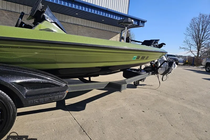 Slide: The Image of 2022 Skeeter FXR21 Apex boat on trailer, parked outdoors under clear blue sky. - 16