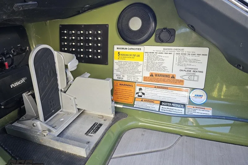 Slide: The Image of 2022 Skeeter FXR21 Apex boat dashboard with control panel and safety warnings. - 65