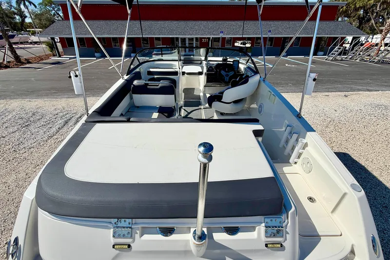 Slide: The Image of 2020 Bayliner VR5 Bowrider OB boat interior with seating and steering wheel, parked outdoors. - 21