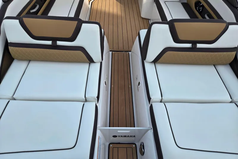 Slide: The Image of 2022 Yamaha Boats 275SD interior with white and tan seating, teak flooring. - 10