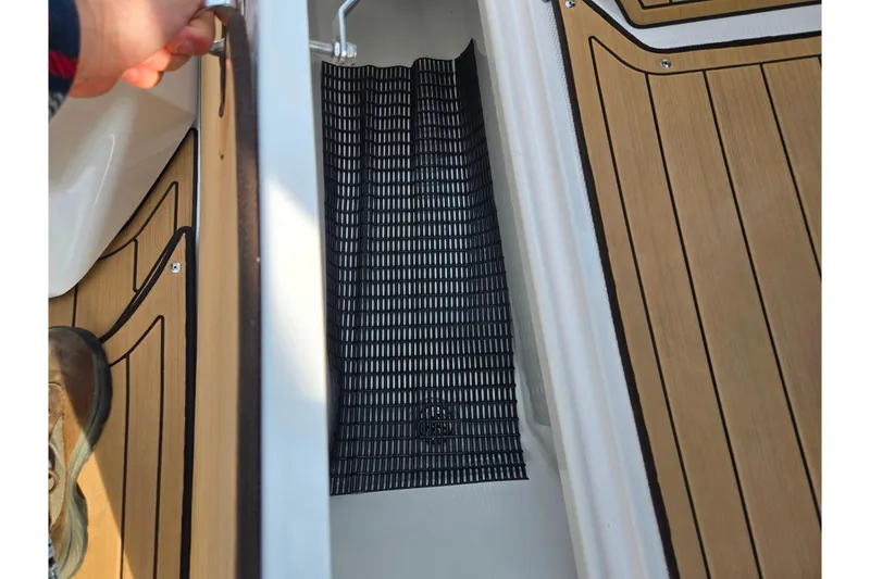 Slide: The Image of 2022 Yamaha Boats 275SD storage compartment with teak flooring and black mat. - 16