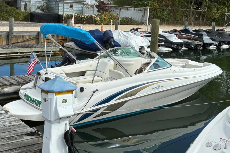 The Image of 1999 Sea Ray 210 Sundeck boat docked with blue canopy and American flag. - 0