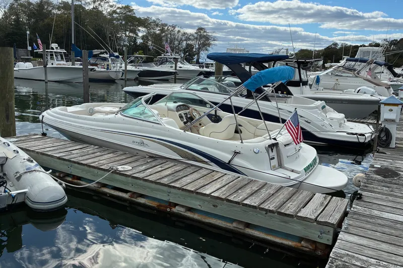 Slide: The Image of 1999 Sea Ray 210 Sundeck boat docked at a marina with American flag. - 3