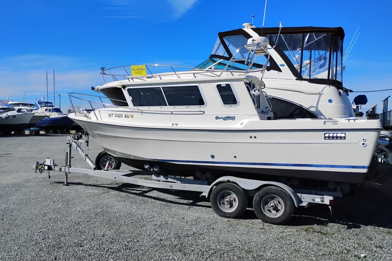 Slide: The Image of 1997 SeaSport Explorer 2400 boat on trailer under clear blue sky. - 1