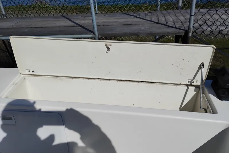 Slide: The Image of Open storage compartment on a 1997 SeaSport Explorer 2400 boat, with shadow and fence background. - 10